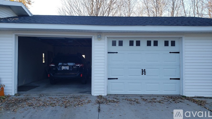 A black car is parked in a white garage.