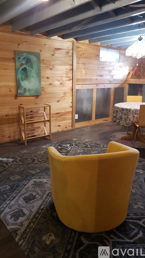 A yellow chair is in the middle of a room with wooden walls.
