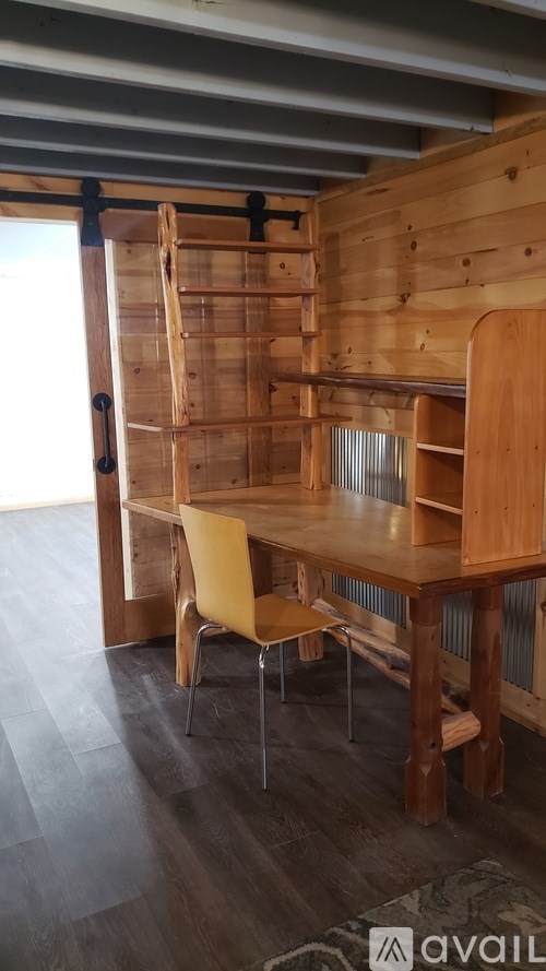 A wooden table with a yellow chair in front of a wooden wall.