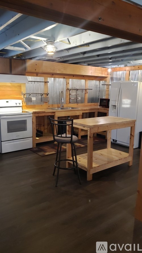 A kitchen with wooden floors and a table with a chair.