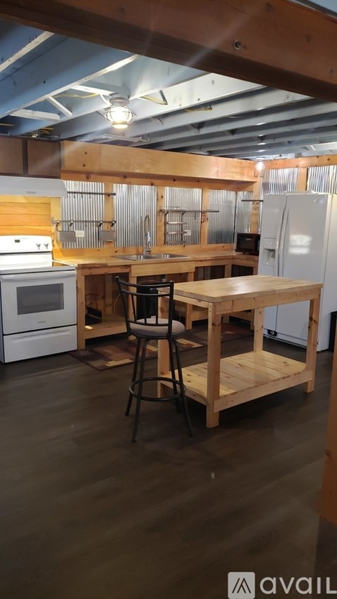 A kitchen with wooden floors and a table with a chair.