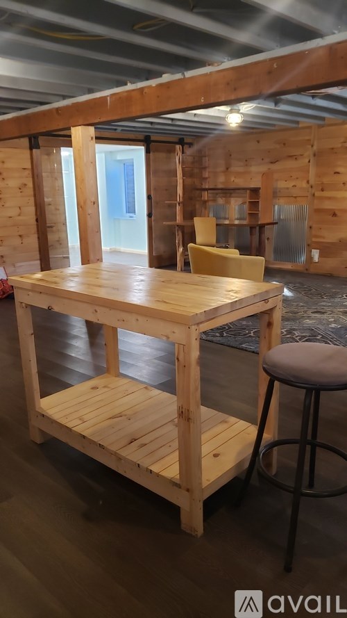 A wooden table with a stool in front of a wooden wall.