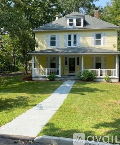 A yellow house with a porch and a white fence.