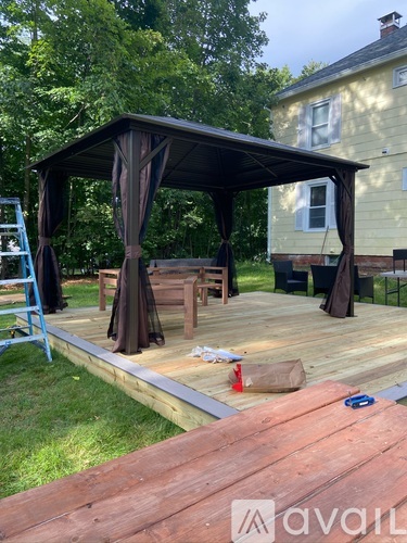 A wooden deck with a gazebo and a ladder.