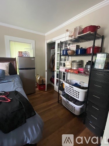 A kitchen pantry with a refrigerator and a shelf with various containers.