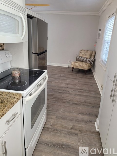 A kitchen with white appliances and a wooden floor.