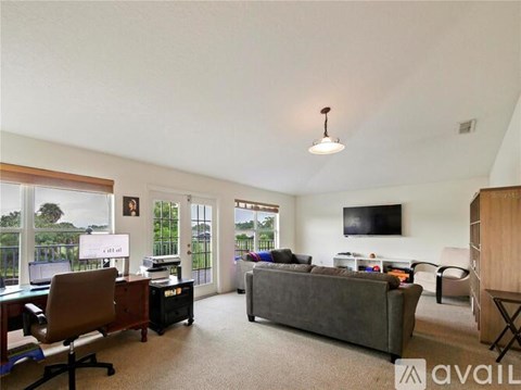 A living room with a grey couch and a television on the wall.