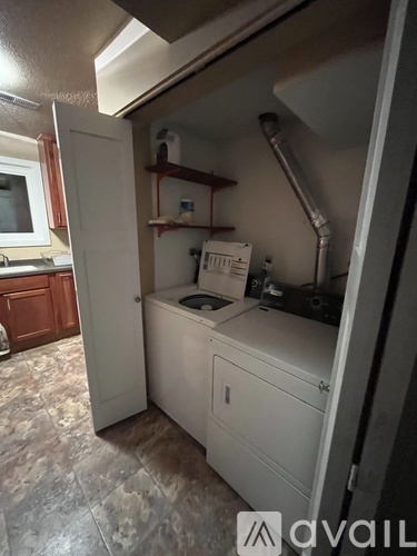 A white dishwasher is in a kitchen with a wooden cabinet.