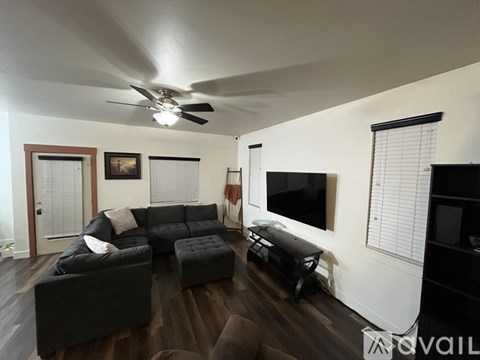 A living room with a black couch and a television on the wall.