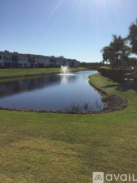 A fountain in the middle of a lake surrounded by grass.