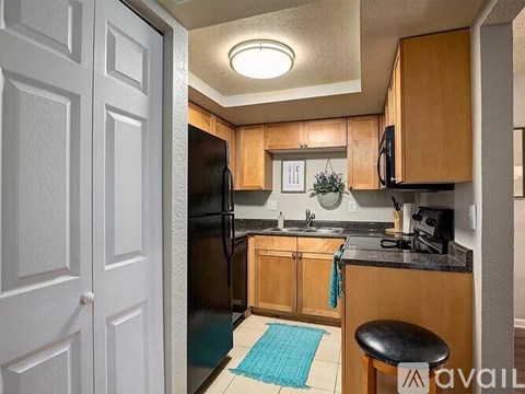 A kitchen with wooden cabinets and a black fridge.