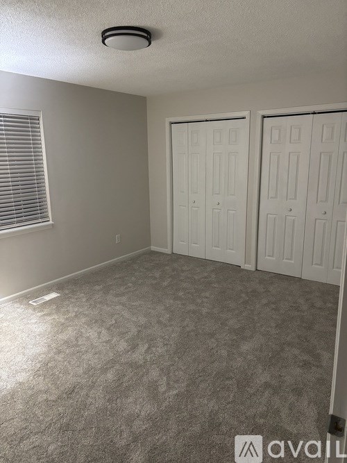 A room with a carpeted floor and two white doors.