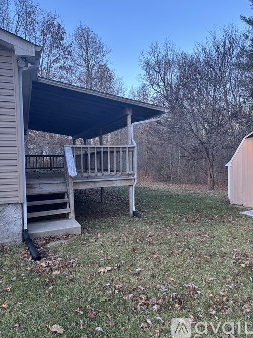 A small wooden deck with a metal railing is in front of a house.