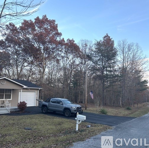 A silver truck is parked in front of a house with a flag on the lawn.