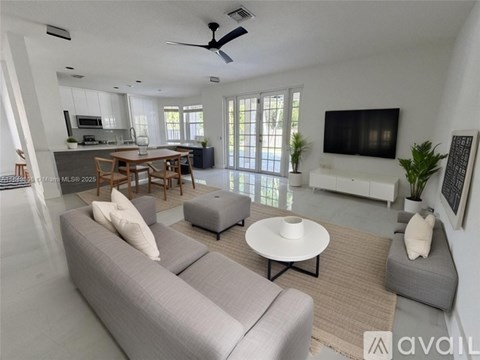 A living room with a grey sofa and a television on the wall.