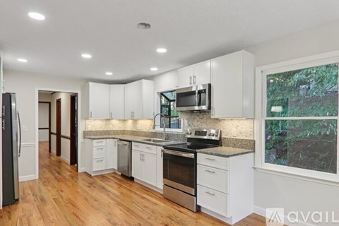 A kitchen with white cabinets and a window.
