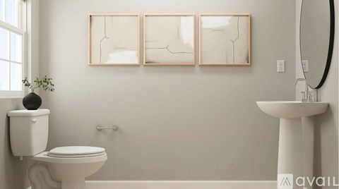A bathroom with a toilet, sink, and three framed pictures on the wall.