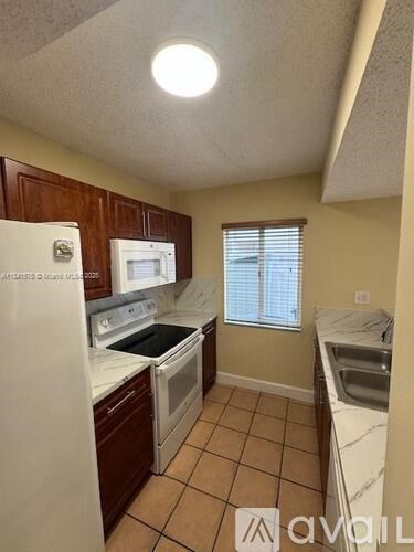 A kitchen with white appliances and brown cabinets.