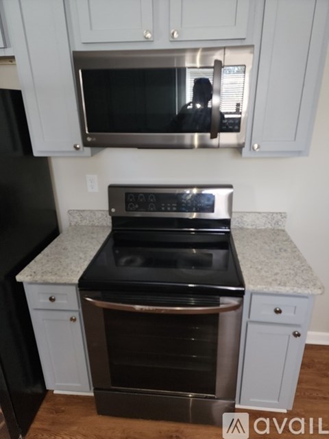 A black refrigerator is in a kitchen with a stainless steel microwave and oven.