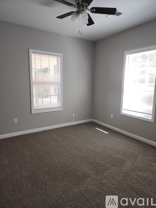 A room with a ceiling fan and two windows.
