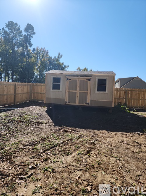A small white trailer is parked in a yard.