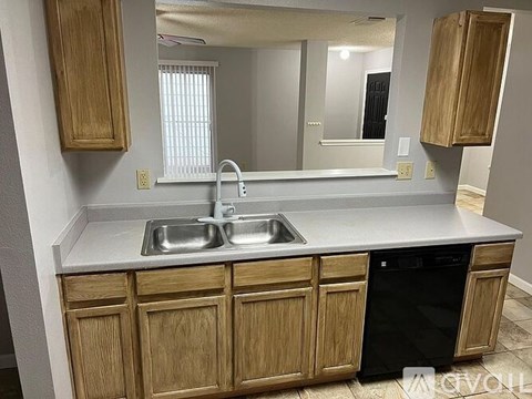 A kitchen with wooden cabinets and a black dishwasher.