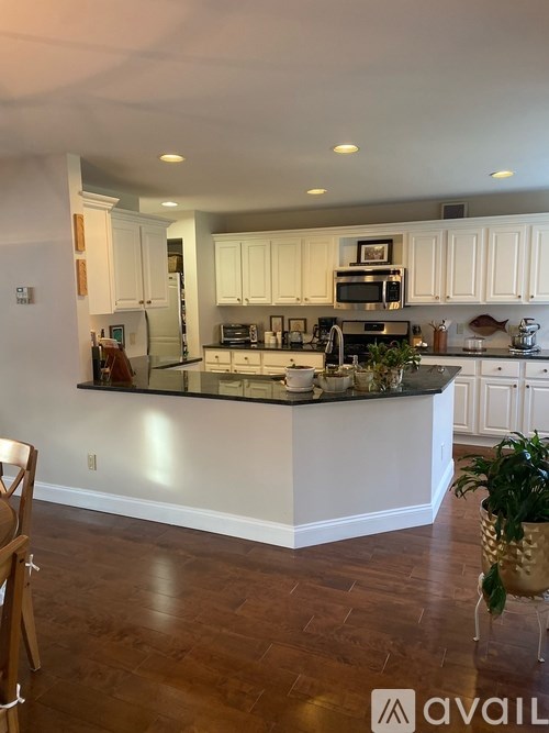 A kitchen with white cabinets and a wooden floor.