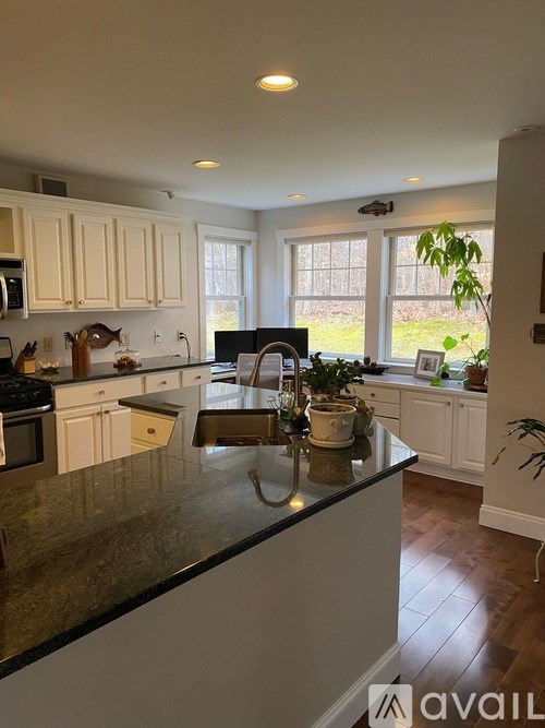 A kitchen with a black countertop and white cabinets.