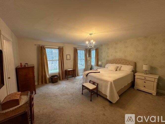 A well-lit bedroom with a large bed, a dresser, and a chandelier.