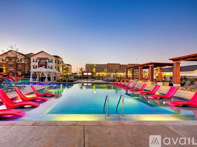 A pool with red chairs and a building in the background.