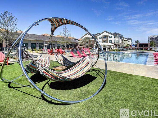 A hammock chair is set up on a grassy area near a pool.