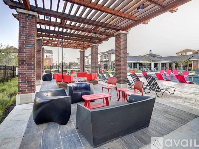 A patio with a black table and red chairs under a wooden pergola.