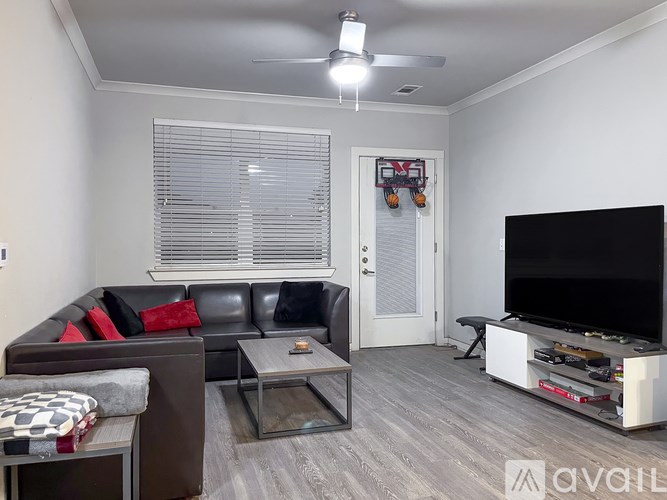 A living room with a black couch, a glass coffee table, and a television.
