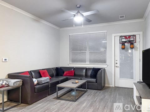 A living room with a black couch and a ceiling fan.