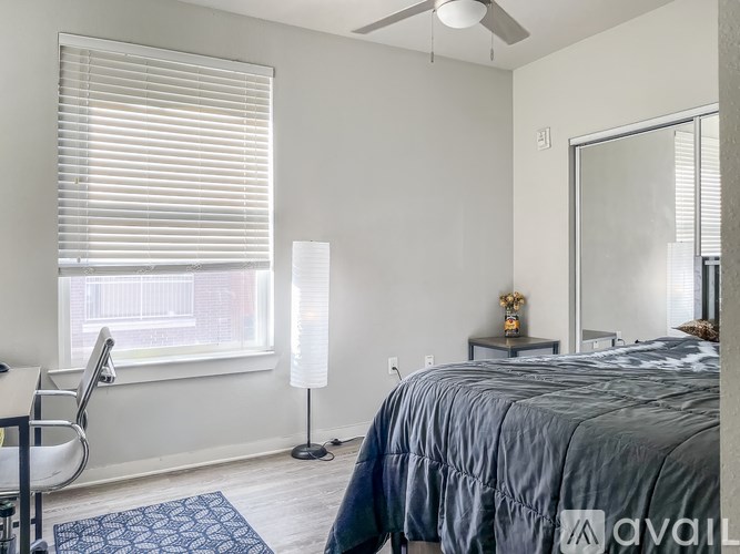A bedroom with a bed, chair, and window with blinds.
