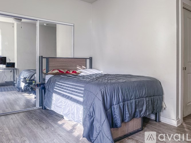 A bedroom with a bed, a mirror, and a wooden headboard.