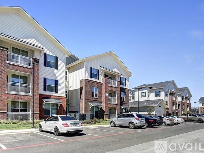 A row of modern apartment buildings with cars parked in front.