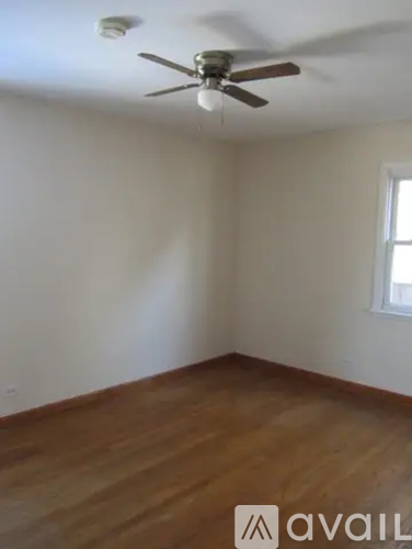 A room with a ceiling fan and wooden flooring.
