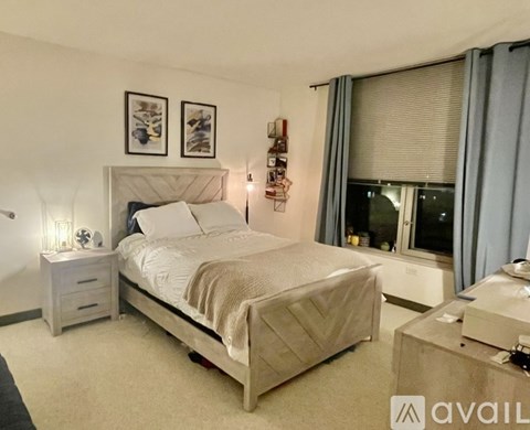 A well-lit bedroom with a large bed and a nightstand with a lamp.