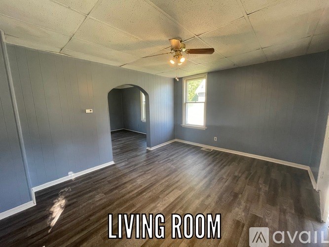 A living room with wood flooring and a ceiling fan.