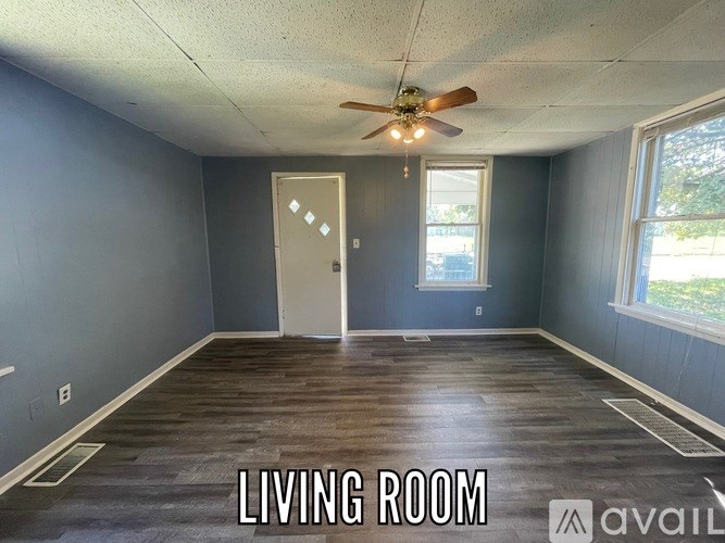 A living room with a ceiling fan and a door.
