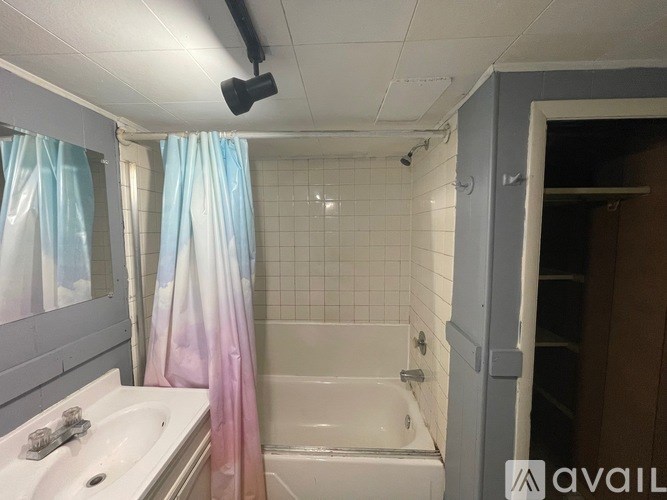 A bathroom with a white sink, a bathtub, and a shower curtain.