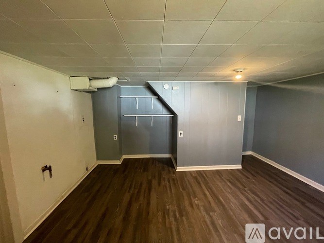 A room with wooden flooring and a grey wall.