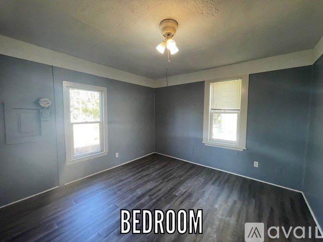 A bedroom with a window and a wooden floor.