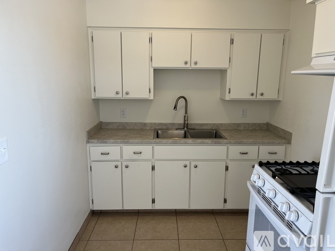 A kitchen with white cabinets and a white stove.