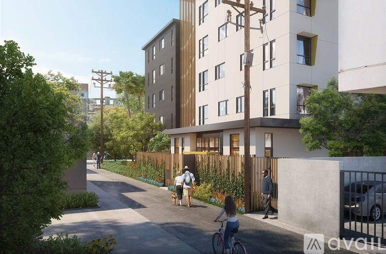 A woman is walking her dog on a sidewalk in front of a modern apartment building.