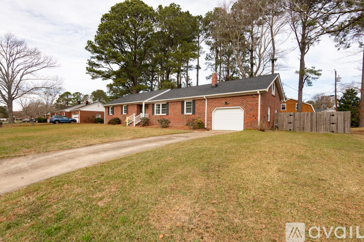 A house with a garage is surrounded by a fence and trees.
