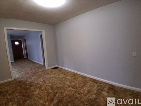 A room with a carpeted floor and a doorway leading to another room.