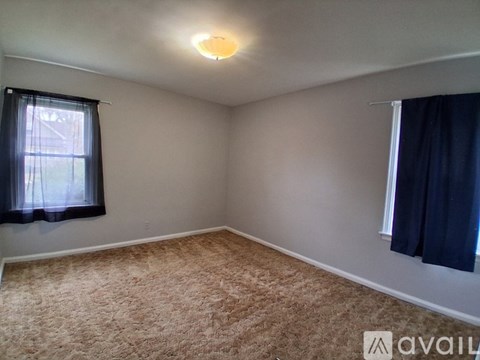 A room with a carpeted floor and a window with curtains.