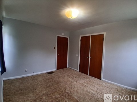 A room with carpeted floor and two doors.